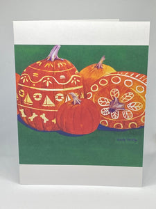 The front of the Seaside Carved Pumpkins with a background of green and white bands on top and below the pumpkins painting.  One pumpkin has sailboats, lifesaving ring, dog biscuits and floral design on top.