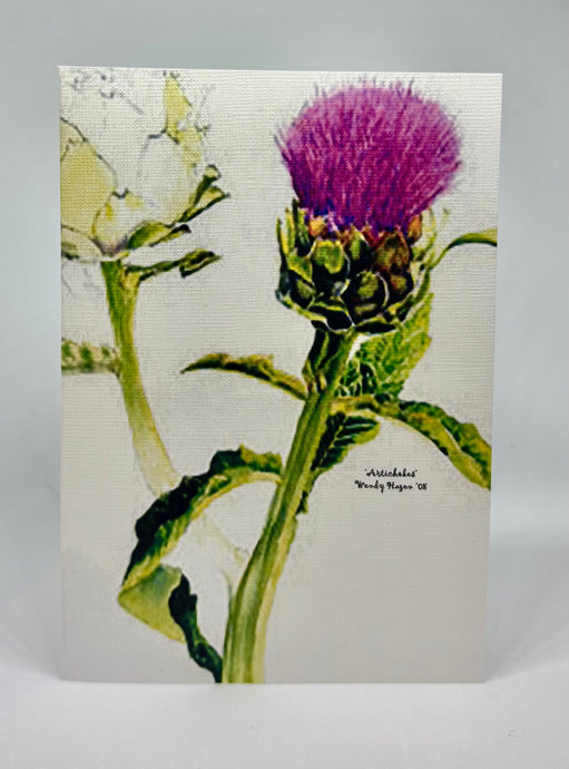 An Artichoke still attached to its stalk with the purplish hue of its 'flower' above.