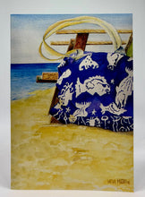 Load image into Gallery viewer, A large blue beach bag next to a wooden beach chair with the water beyond.
