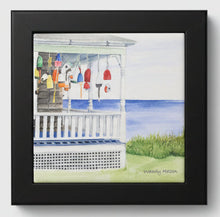 Load image into Gallery viewer, A ceramic tile with lobster buoys hanging from the porch beams looking out to sea on the cliff's edge with a black wooden frame.