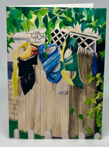 Lifejackets drying on the stockade walls of the outdoor shower.  The shower head is peeking up above and there is lattice work on the house as well as a tree branch acting as a canopy for the shower.