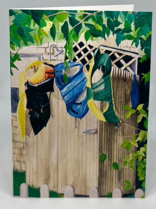 Lifejackets drying on the stockade walls of the outdoor shower.  The shower head is peeking up above and there is lattice work on the house as well as a tree branch acting as a canopy for the shower.