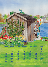 Load image into Gallery viewer, A watercolor-style May calendar page featuring a small wooden shed by a cove on the river, colorful flowers, and a blue grid of days of the week at the bottom.