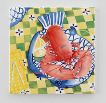 Load image into Gallery viewer, on a yellow, white and green checked tablecloth sits a blue and white large fish shaped dish with a cooked red lobster with hot butter and a wedge of lemon off to the side.