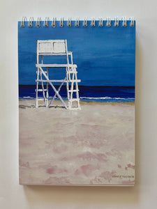 a tall white lifeguard stand looking towards the brewing ocean