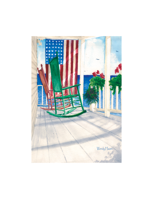 Colorful green and red rocking chairs on a deck with an American flag and ocean view