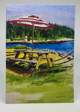 Load image into Gallery viewer, McLoon&#39;s Lobster Shack Picnic Table by the working harbor.  There is grass surrounding the table with a well worn path created by the many diners.  The red and white umbrella is a perfect foil for redirecting the sun.  This season opens May 24, 2025!  Bon Appétit!