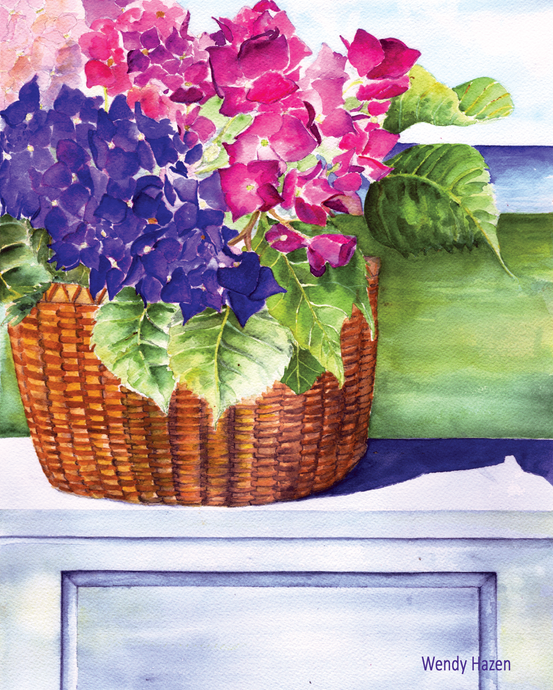 Aa Nantucket basket filled with colorful hydrangeas sitting on a terrace wall looking towards the sea.