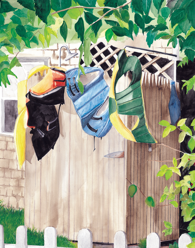 This outdoor shower has the life jackets hanging off the picket fence  enclosure drying .  The jackets are orange , black, yellow, blue and green.