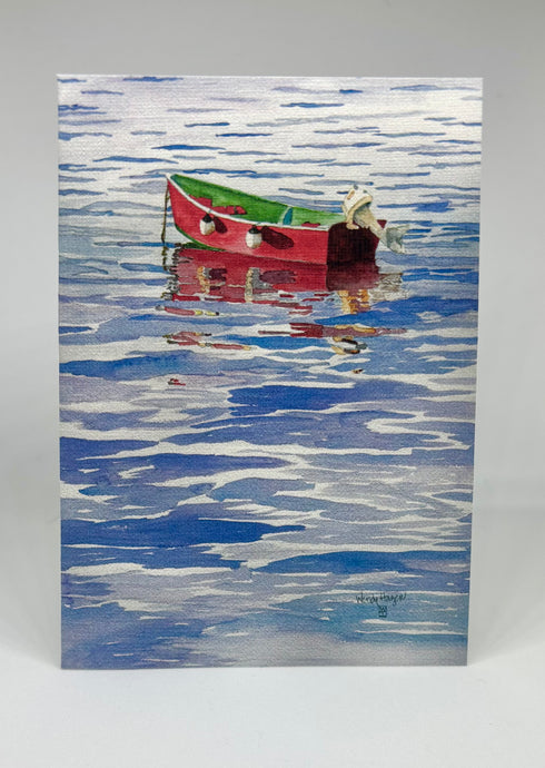 A red skiff with the motor tilted up sitting at anchor.