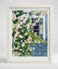 Load image into Gallery viewer, Framed artwork of a Siasconset cottage with roses climbing up the side of the house. There is a window looking through to another window with sheets hanging on a clothesline.