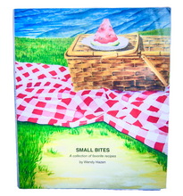 Load image into Gallery viewer, Front cover with a gingham picnic cloth and a wicker basket