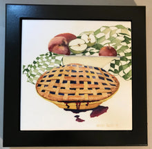 Load image into Gallery viewer, A pie with criss cross crust on top with a bit of the berry juice running down the front of the pie plate.  And a bowl with apples and a green gingham drying towel in the background.  Surrounded by a black wooden frame.