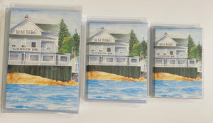 3 different sizes of the Albonegon Inn perched on the rocks with the water flowing by.
